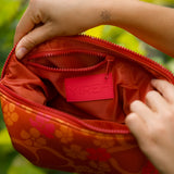 woman holding expandable puakenikeni printed neoprene pouch with detachable mini pouches
