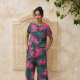 woman with brown hair wearing dark green boxy t-shirt blouse with button-back closure, with fern and ginger print