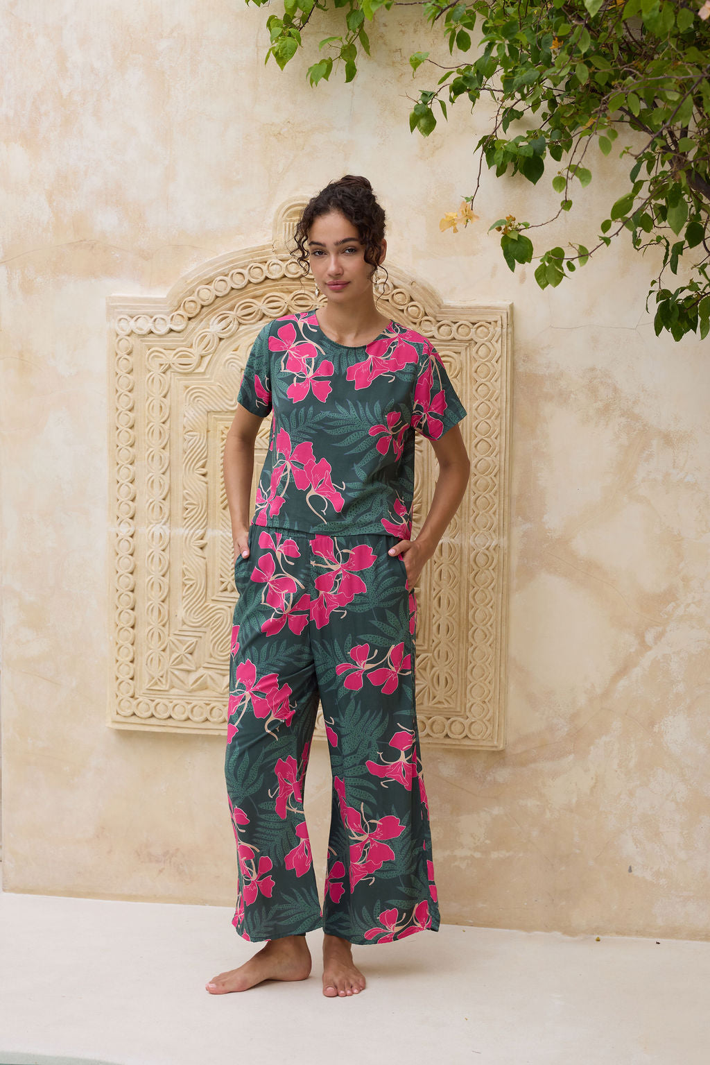 woman with brown hair wearing dark green flowy pants with fern and ginger print