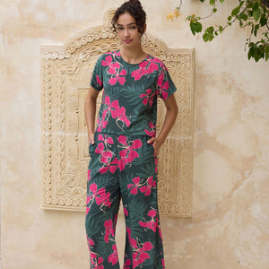 woman with brown hair wearing dark green flowy pants with fern and ginger print