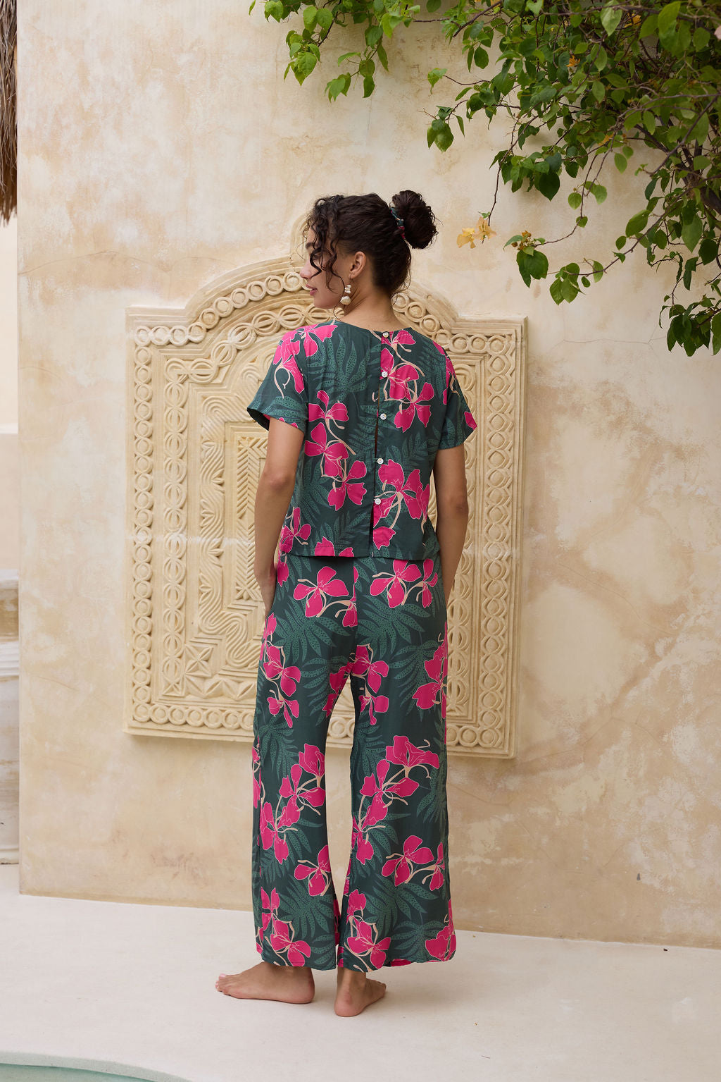 woman with brown hair wearing dark green flowy pants with fern and ginger print