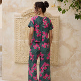 woman with brown hair wearing dark green flowy pants with fern and ginger print