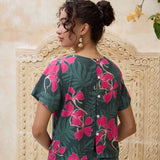 woman with brown hair wearing dark green boxy t-shirt blouse with button-back closure, with fern and ginger print