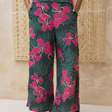 woman with brown hair wearing dark green flowy pants with fern and ginger print