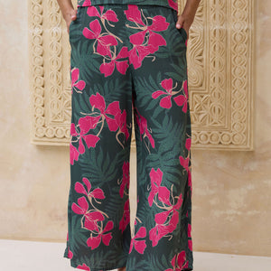 woman with brown hair wearing dark green flowy pants with fern and ginger print