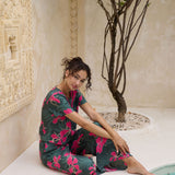 woman with brown hair wearing dark green flowy pants with fern and ginger print