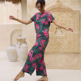 woman with brown hair wearing dark green flowy pants with fern and ginger print
