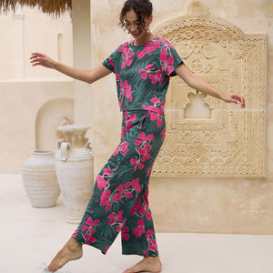 woman with brown hair wearing dark green flowy pants with fern and ginger print