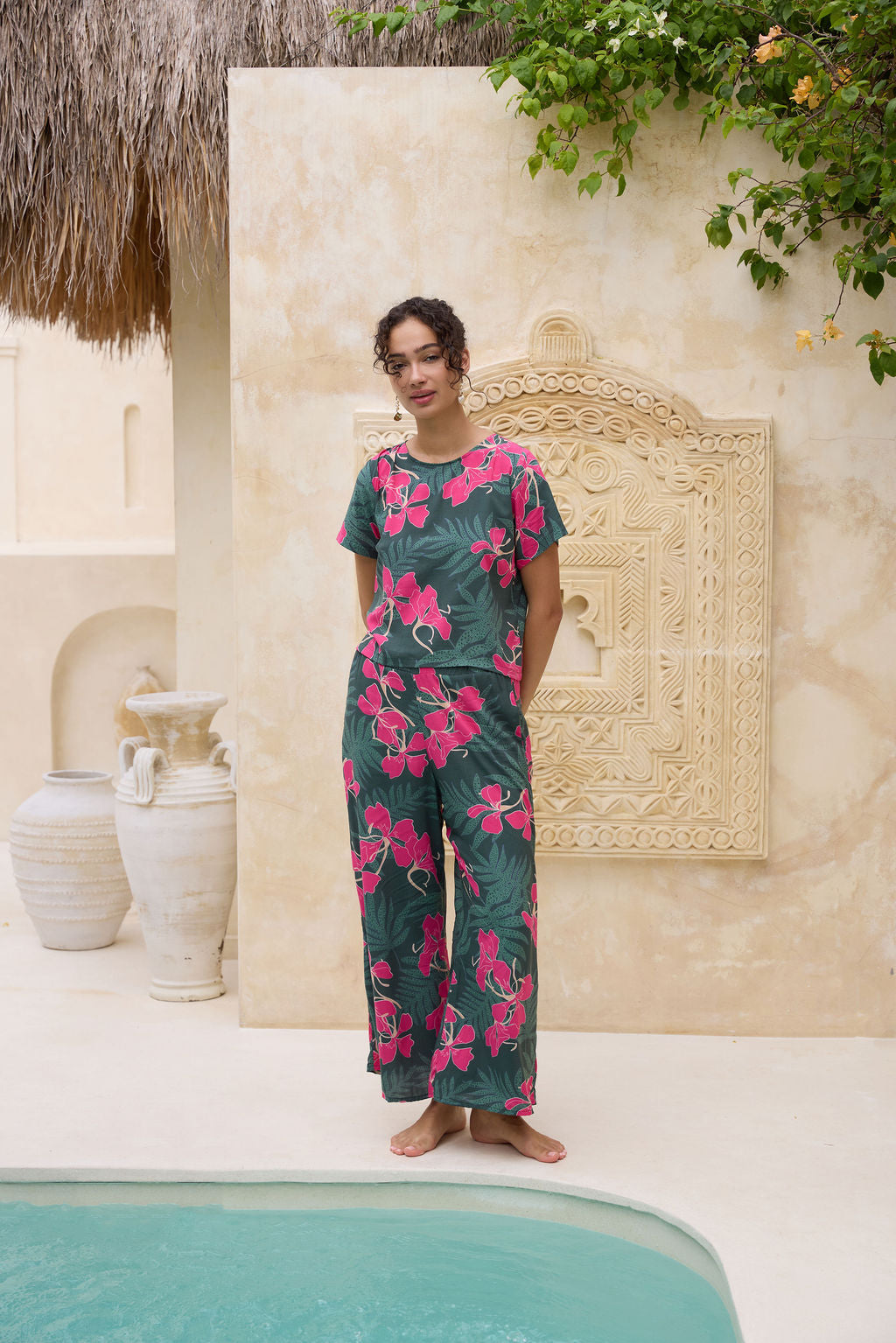 woman with brown hair wearing dark green flowy pants with fern and ginger print
