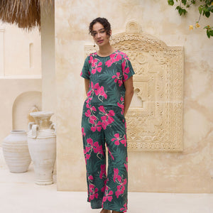 woman with brown hair wearing dark green flowy pants with fern and ginger print