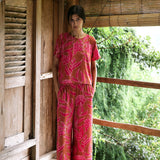 A woman with dark hair wears a YIREH t-shirt top with shell button back. It is the Noe Top in the Garden 'Awapuhi print. 