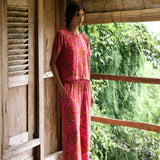 A woman with dark hair wears a YIREH t-shirt top with shell button back. It is the Noe Top in the Garden 'Awapuhi print. 