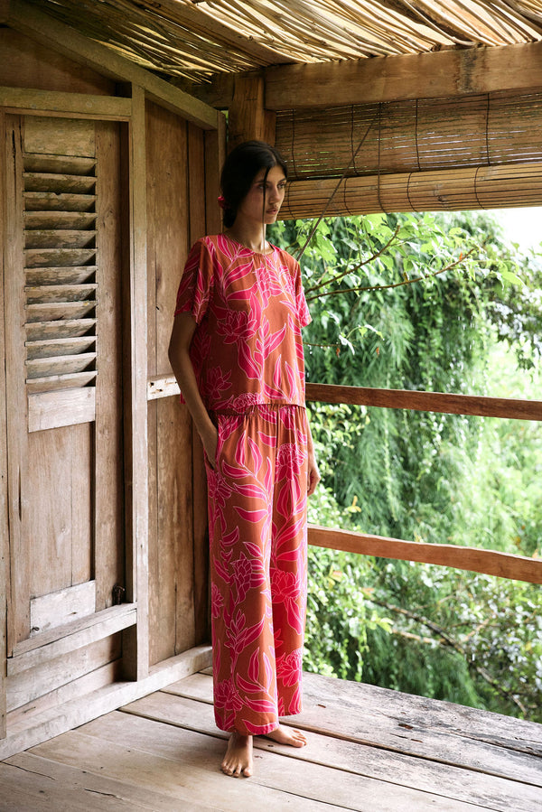 A woman with dark hair wears a YIREH wide legged pant with elastic waistband. It is the Elodi Pant in the Garden 'Awapuhi print. 