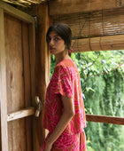 A woman with dark hair wears a YIREH t-shirt top with shell button back. It is the Noe Top in the Garden 'Awapuhi print. 