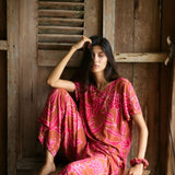 A woman with dark hair wears a YIREH t-shirt top with shell button back. It is the Noe Top in the Garden 'Awapuhi print. 