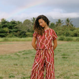 woman with brown hair wearing red-brown colored top with button closure back and lei print