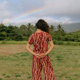 woman with brown hair wearing red-brown colored top with button closure back and lei print