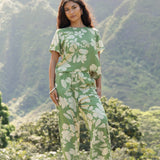 woman wearing green matching top and pant set with native Hawaiian plants 