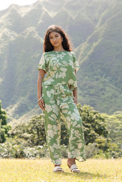 woman wearing green matching top and pant set with native Hawaiian plants 