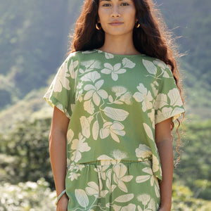 woman wearing green matching top and pant set with native Hawaiian plants 