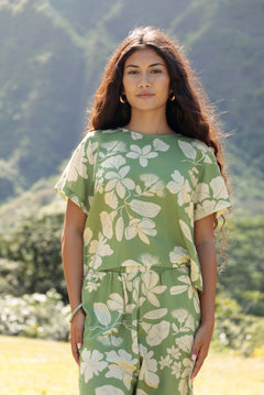 woman wearing green matching top and pant set with native Hawaiian plants 
