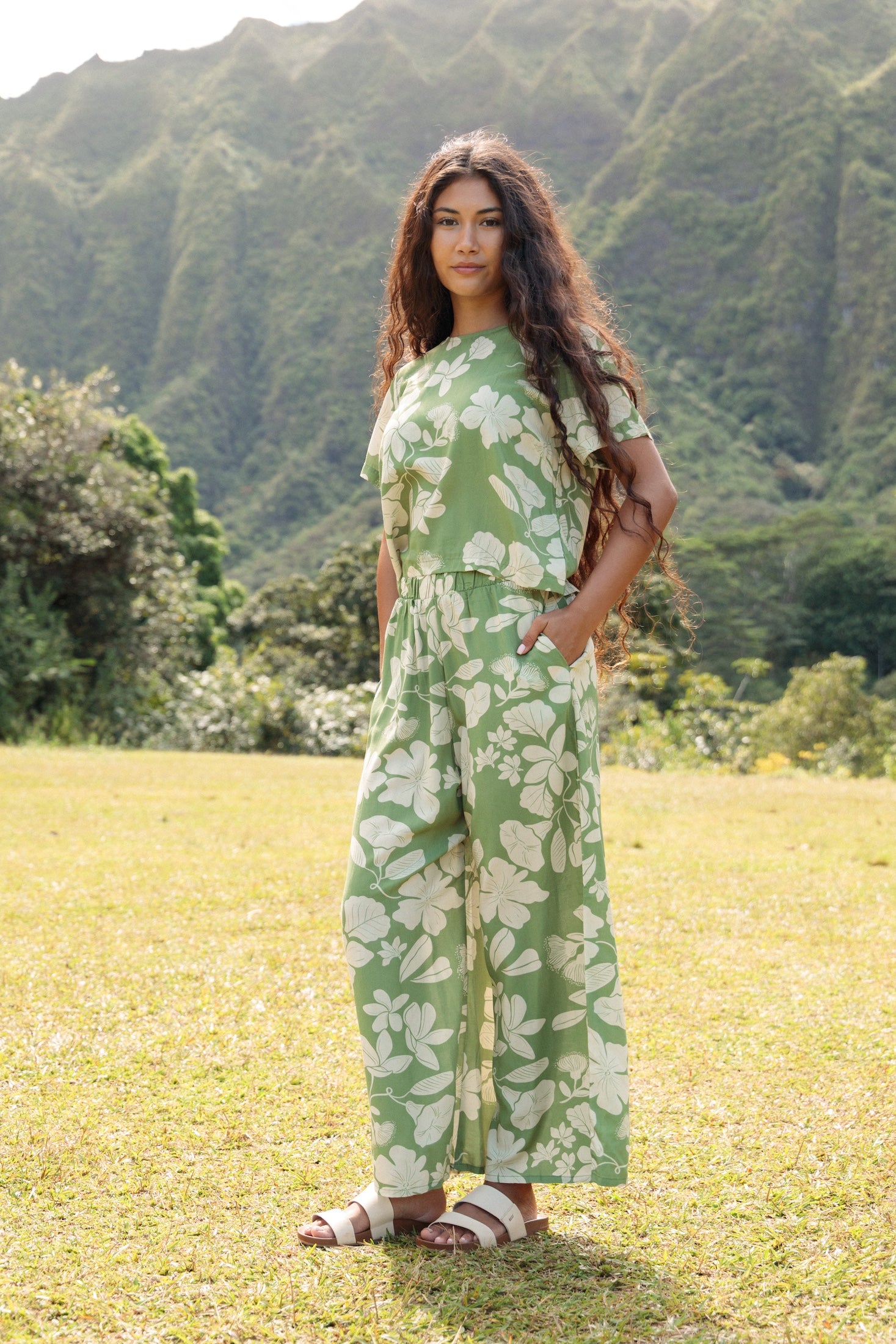 woman wearing green matching top and pant set with native Hawaiian plants 