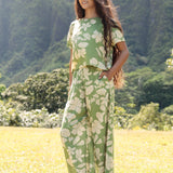 woman wearing green matching top and pant set with native Hawaiian plants 