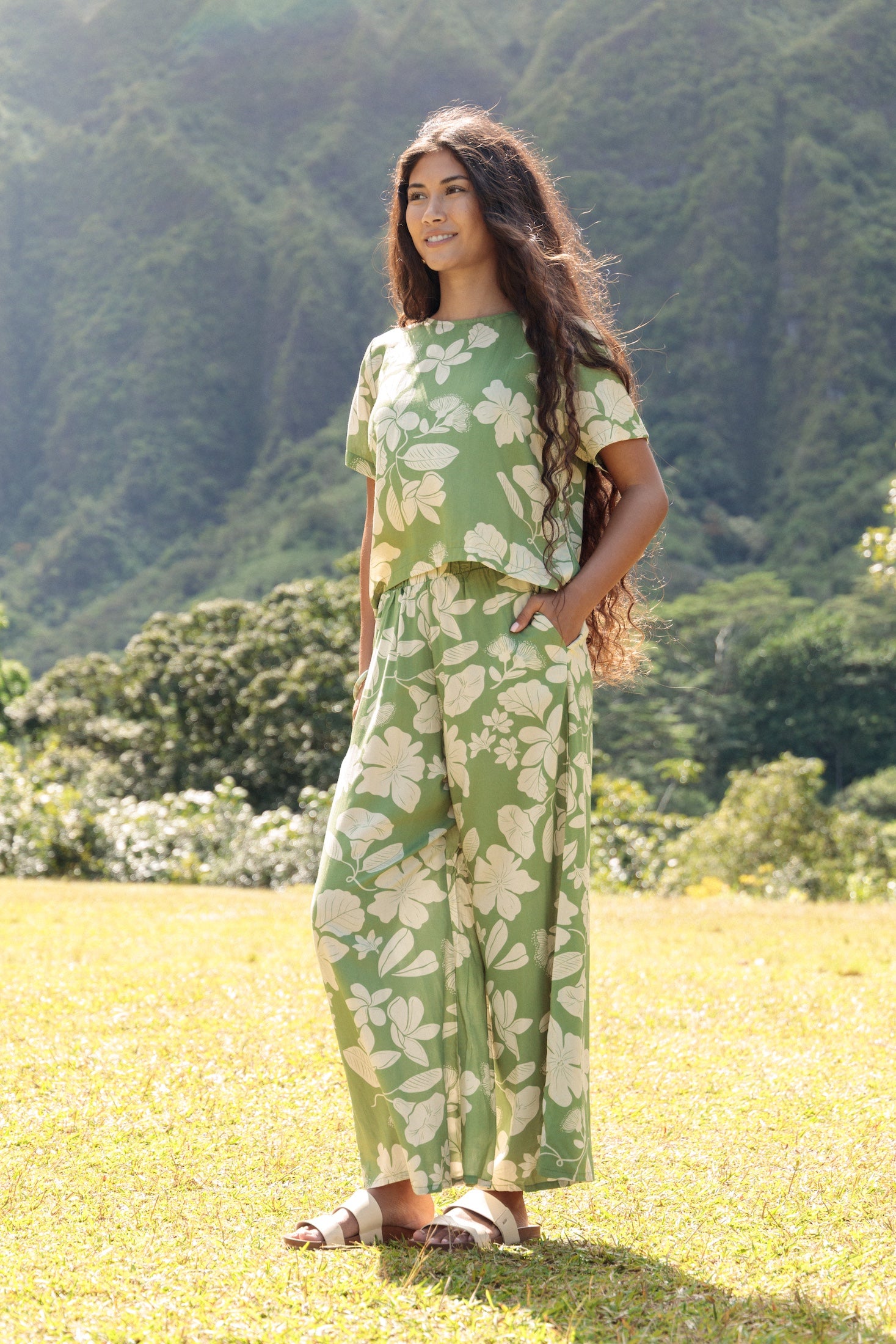 woman wearing green matching top and pant set with native Hawaiian plants 