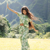 woman wearing green matching top and pant set with native Hawaiian plants 