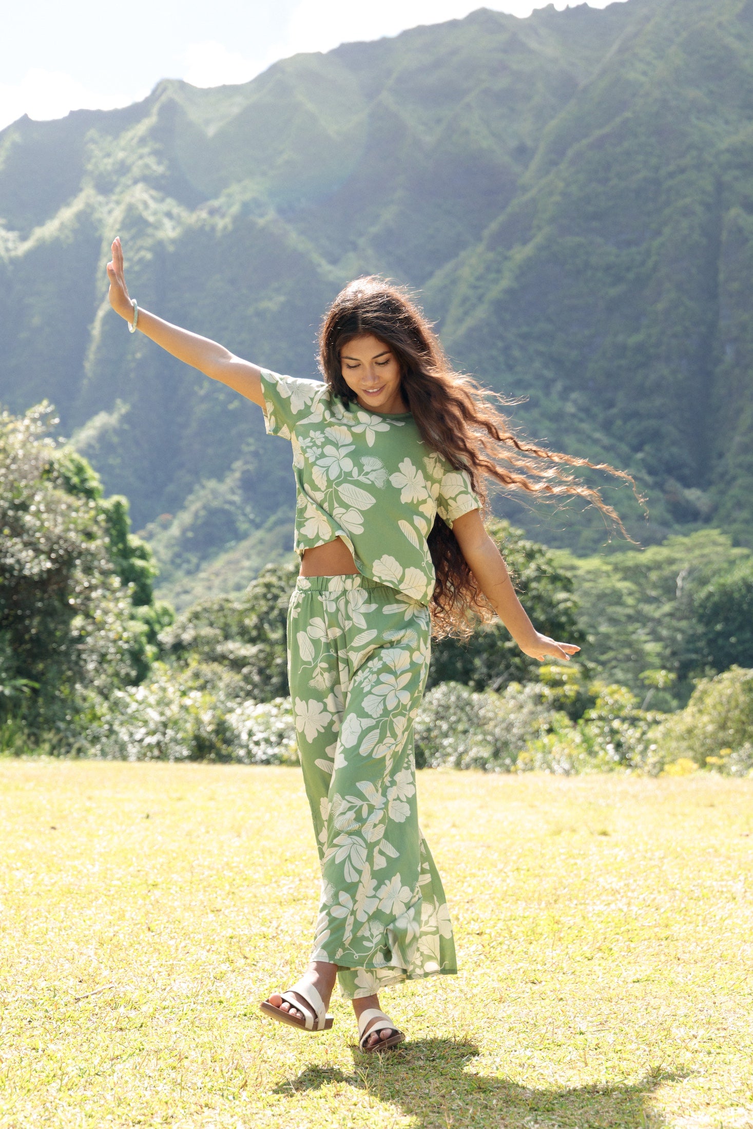 woman wearing green matching top and pant set with native Hawaiian plants 