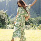 woman wearing green matching top and pant set with native Hawaiian plants 