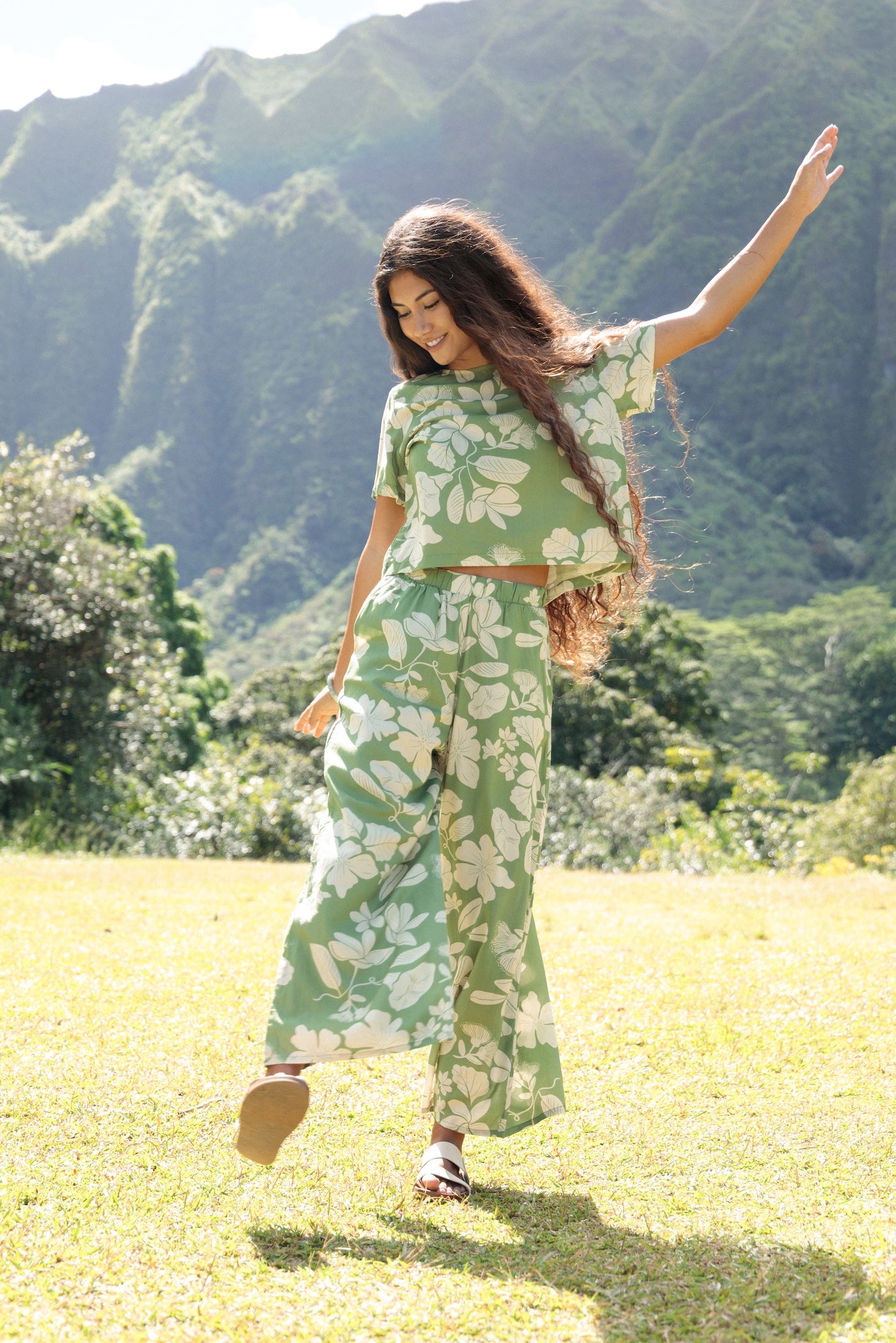 woman wearing green matching top and pant set with native Hawaiian plants 