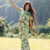 woman wearing green matching top and pant set with native Hawaiian plants 