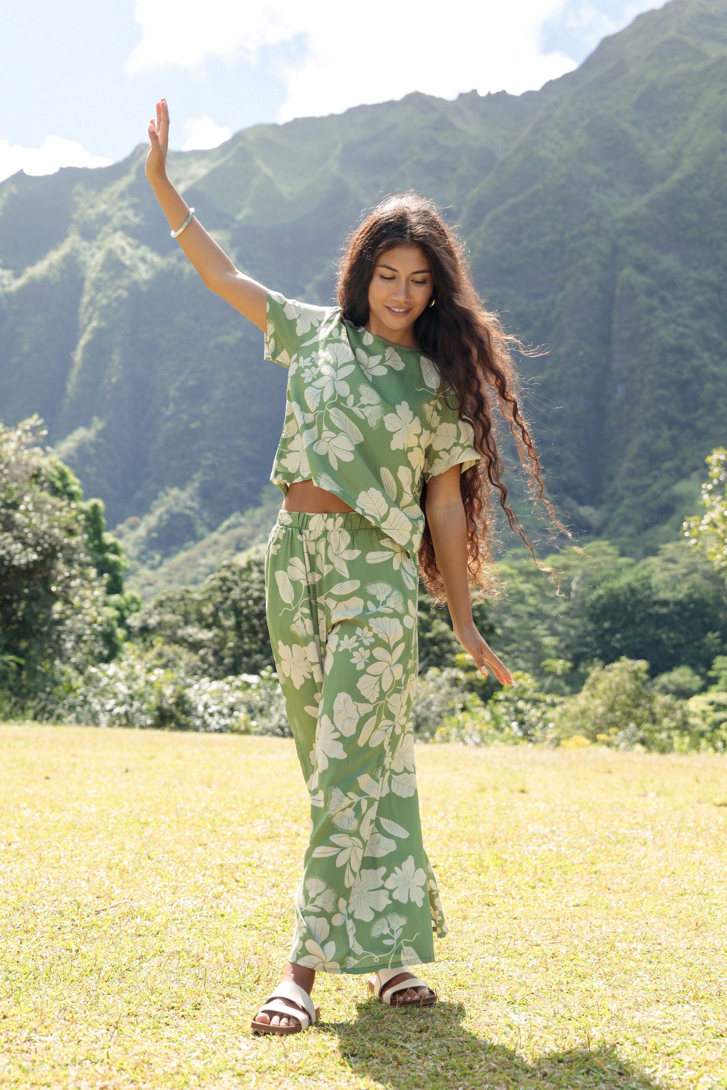 woman wearing green matching top and pant set with native Hawaiian plants 