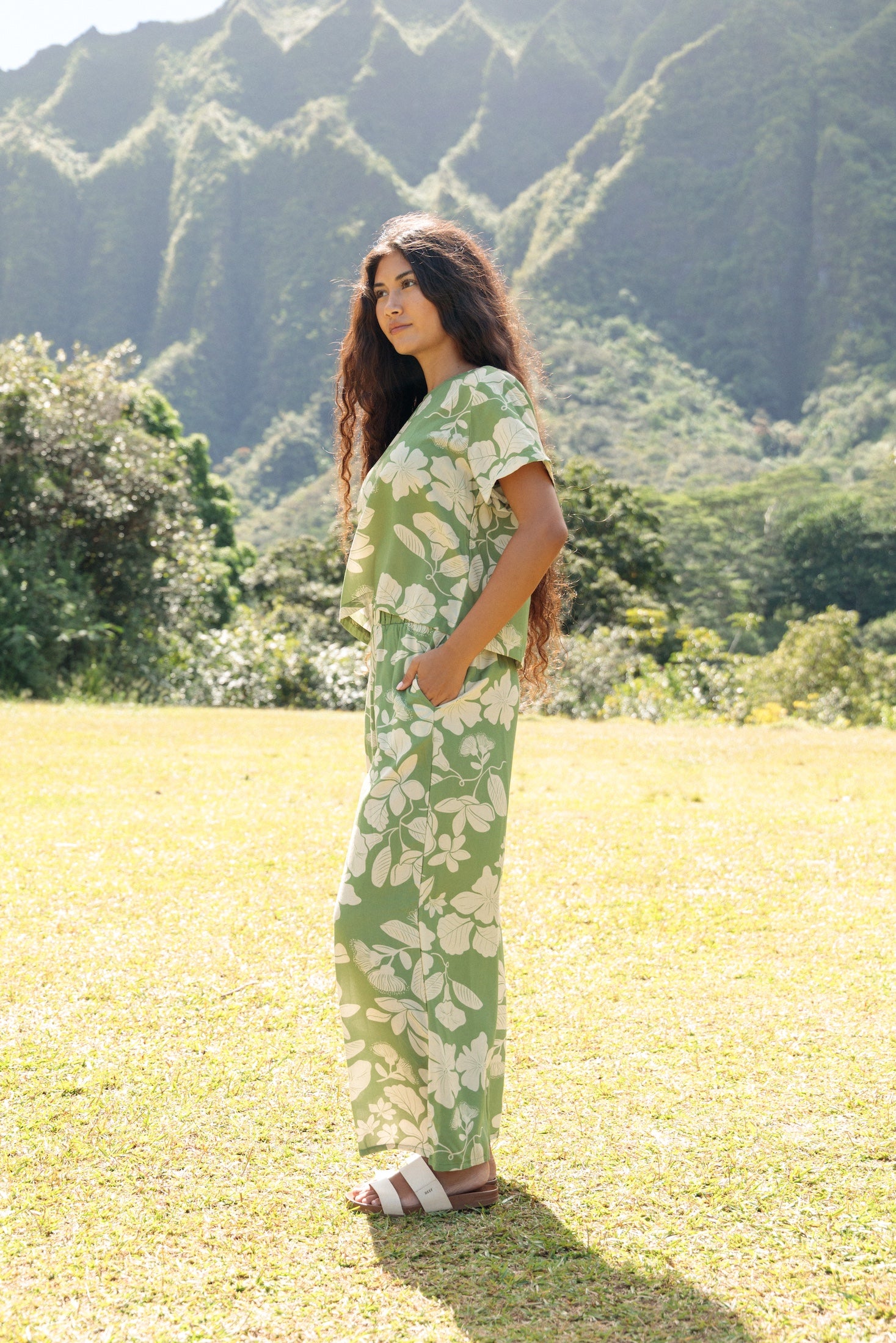 woman wearing green matching top and pant set with native Hawaiian plants 