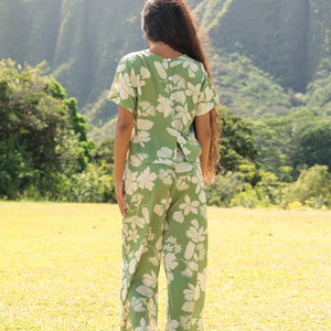 woman wearing green matching top and pant set with native Hawaiian plants 