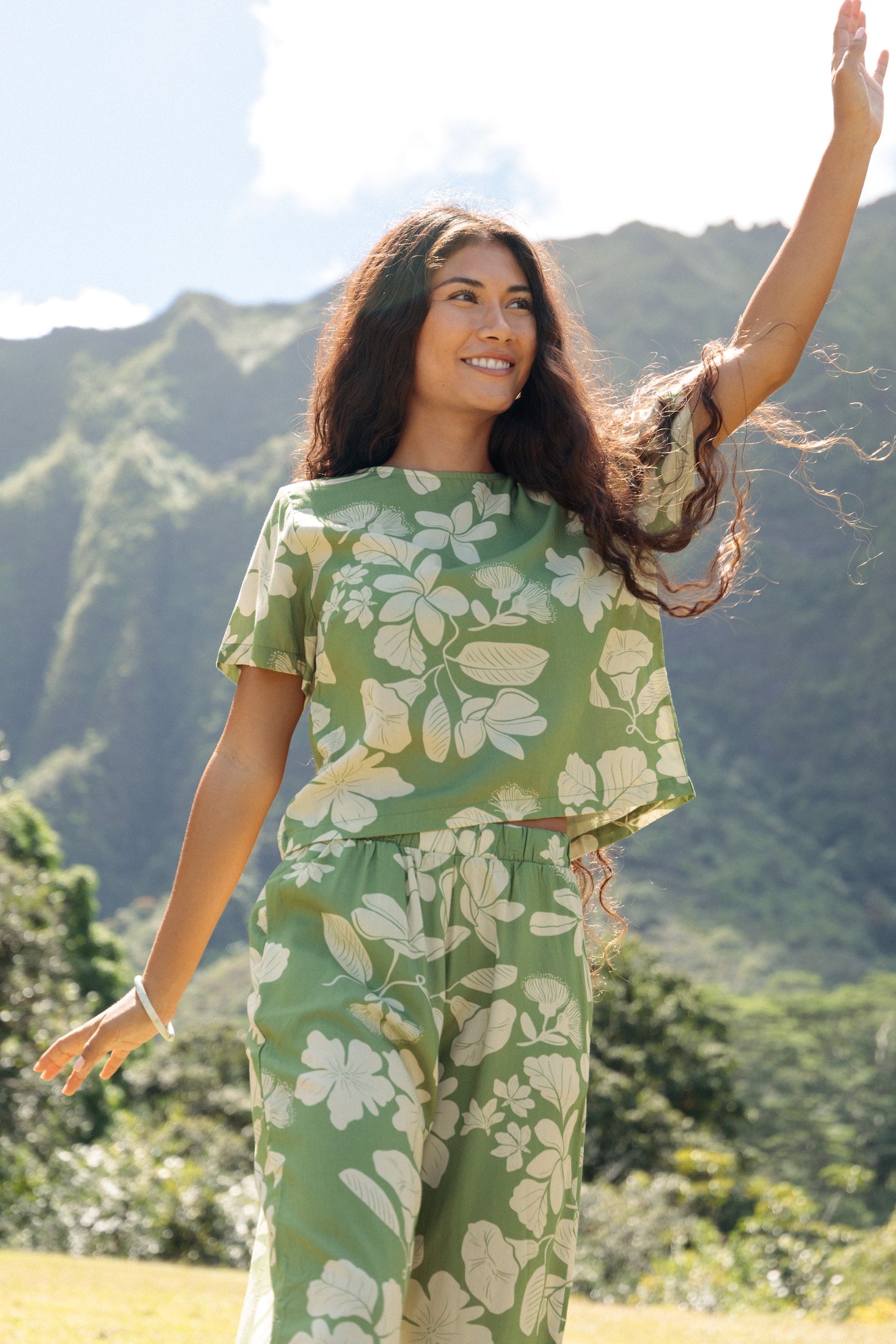 woman wearing green matching top and pant set with native Hawaiian plants 