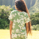 woman wearing green matching top and pant set with native Hawaiian plants 