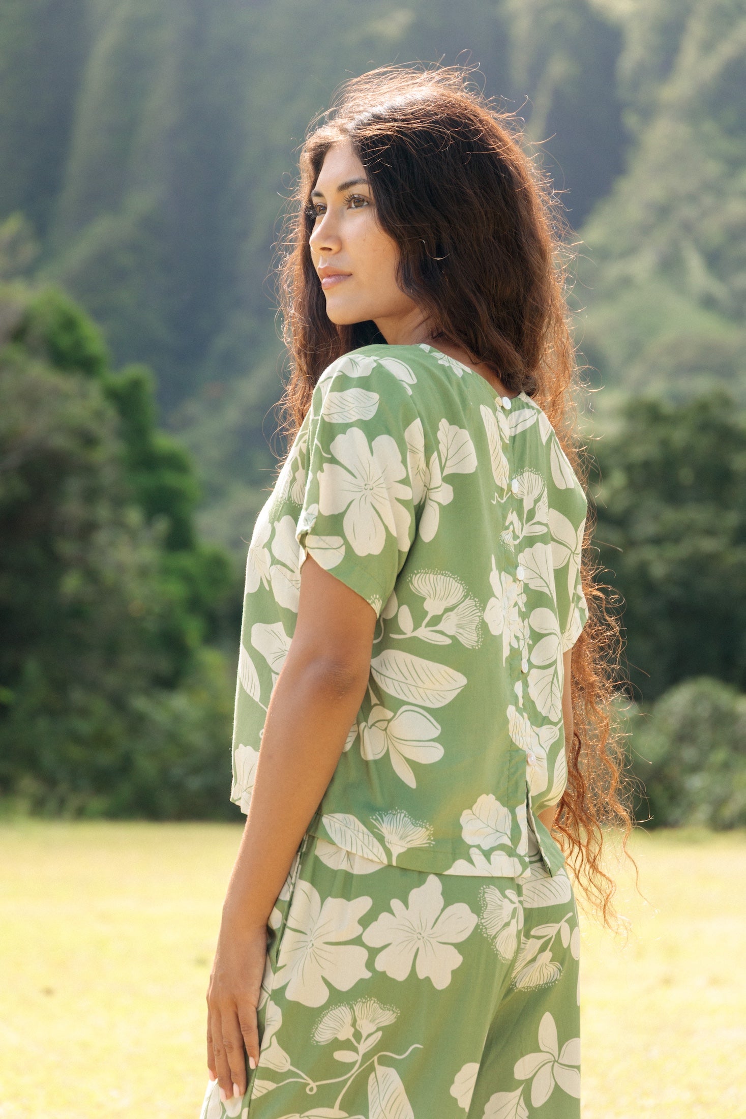 woman wearing green matching top and pant set with native Hawaiian plants 