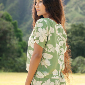 woman wearing green matching top and pant set with native Hawaiian plants 