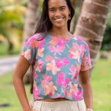 woman with brown hair wearing a teal t-shirt top with orange and pink foral print