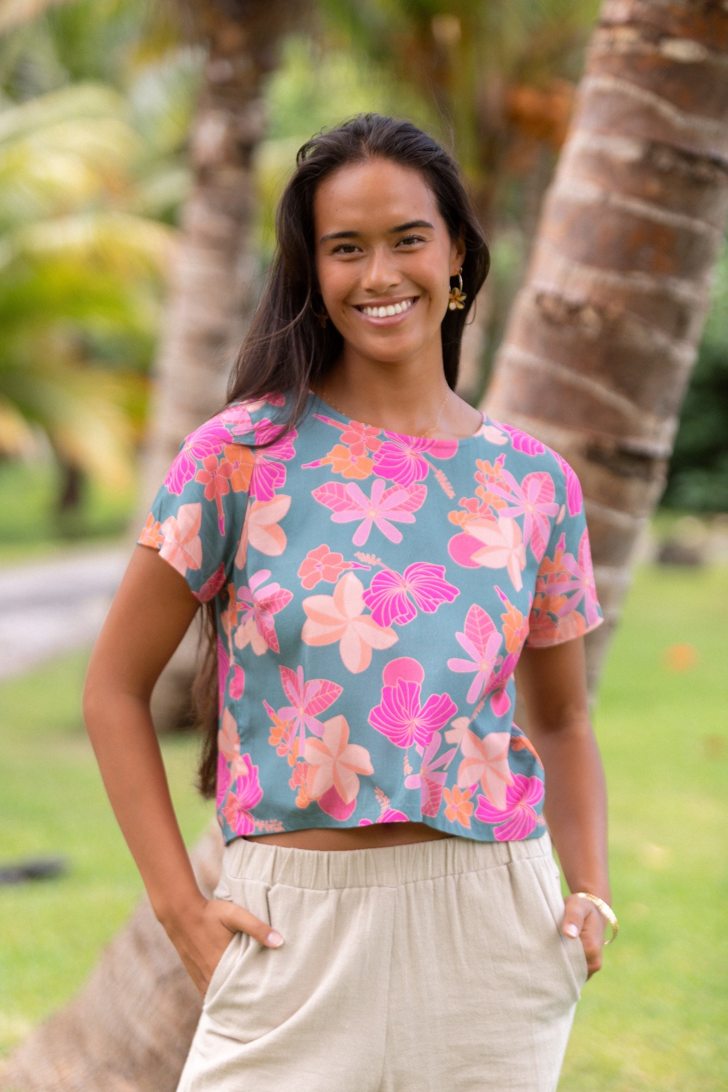 woman with brown hair wearing a teal t-shirt top with orange and pink foral print