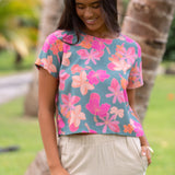 woman with brown hair wearing a teal t-shirt top with orange and pink foral print