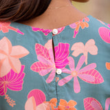 woman with brown hair wearing a teal t-shirt top with orange and pink foral print