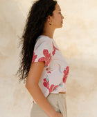 Woman in short sleeve tee shirt with red floral print on beige ground.