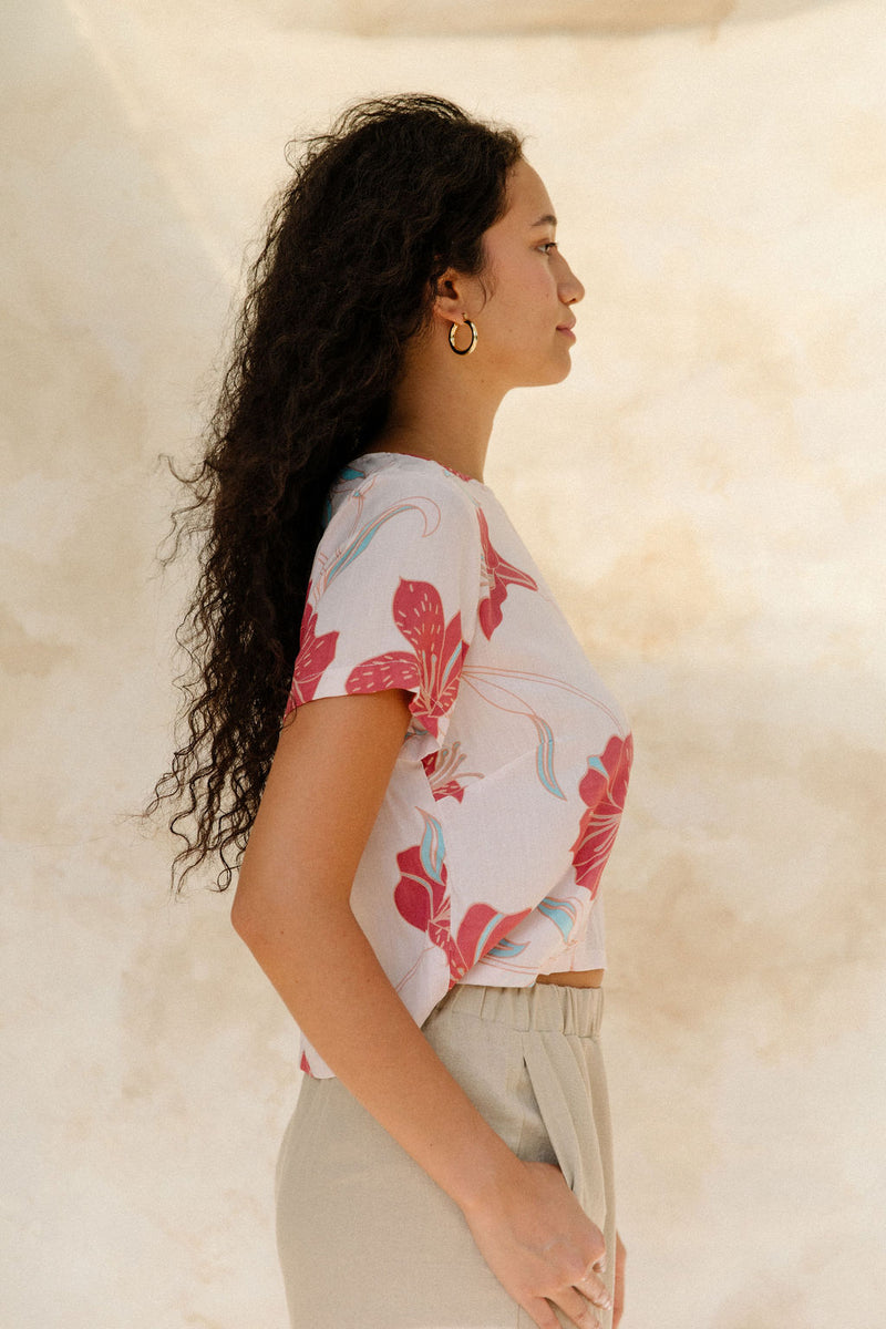 Woman in short sleeve tee shirt with red floral print on beige ground.