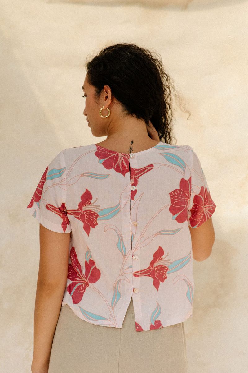 Woman in short sleeve tee shirt with red floral print on beige ground.