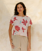 Woman in short sleeve tee shirt with red floral print on beige ground.