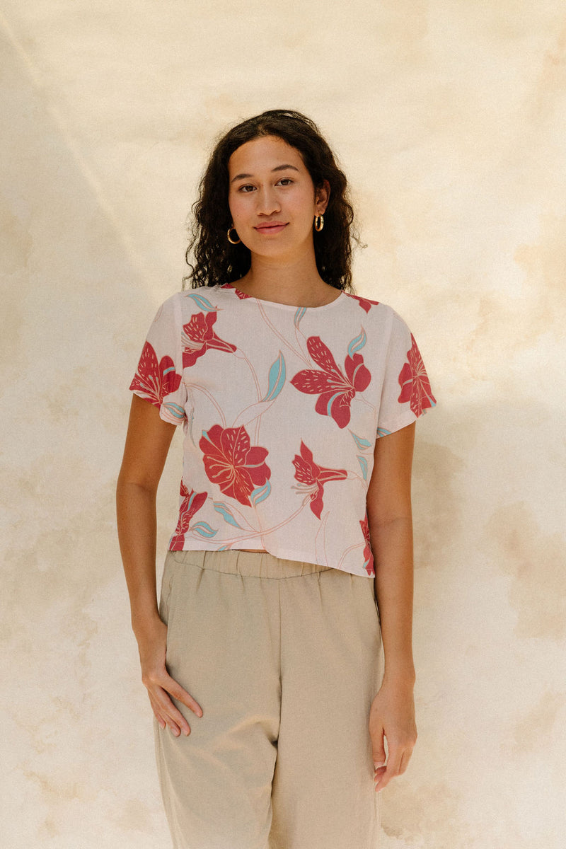 Woman in short sleeve tee shirt with red floral print on beige ground.