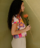 Woman wearing short sleeve tee with bright multi colored floral print on light pink ground.